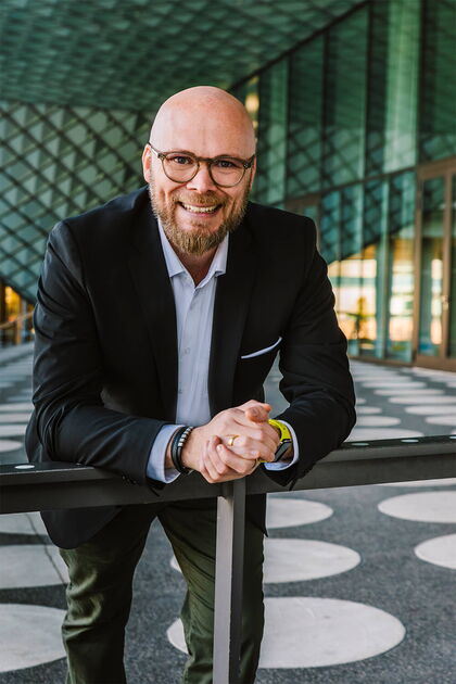 Ein Bild des Bayerischen Digitalministers Dr. Fabian Mehring, der nach vorne gelehnt in einem modernen Gebäude steht.